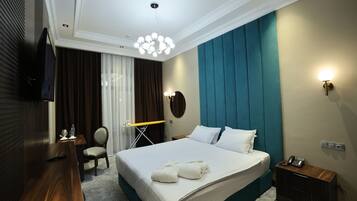 Habitación de hotel con una cama grande, un televisor de pantalla plana montado en la pared, un escritorio con una silla y una mesita con lámpara.