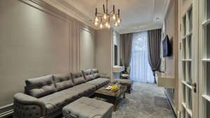 A modern living room with a grey sectional sofa, a coffee table, and a television mounted on the wall. - Continental Hotel (Samarkand)