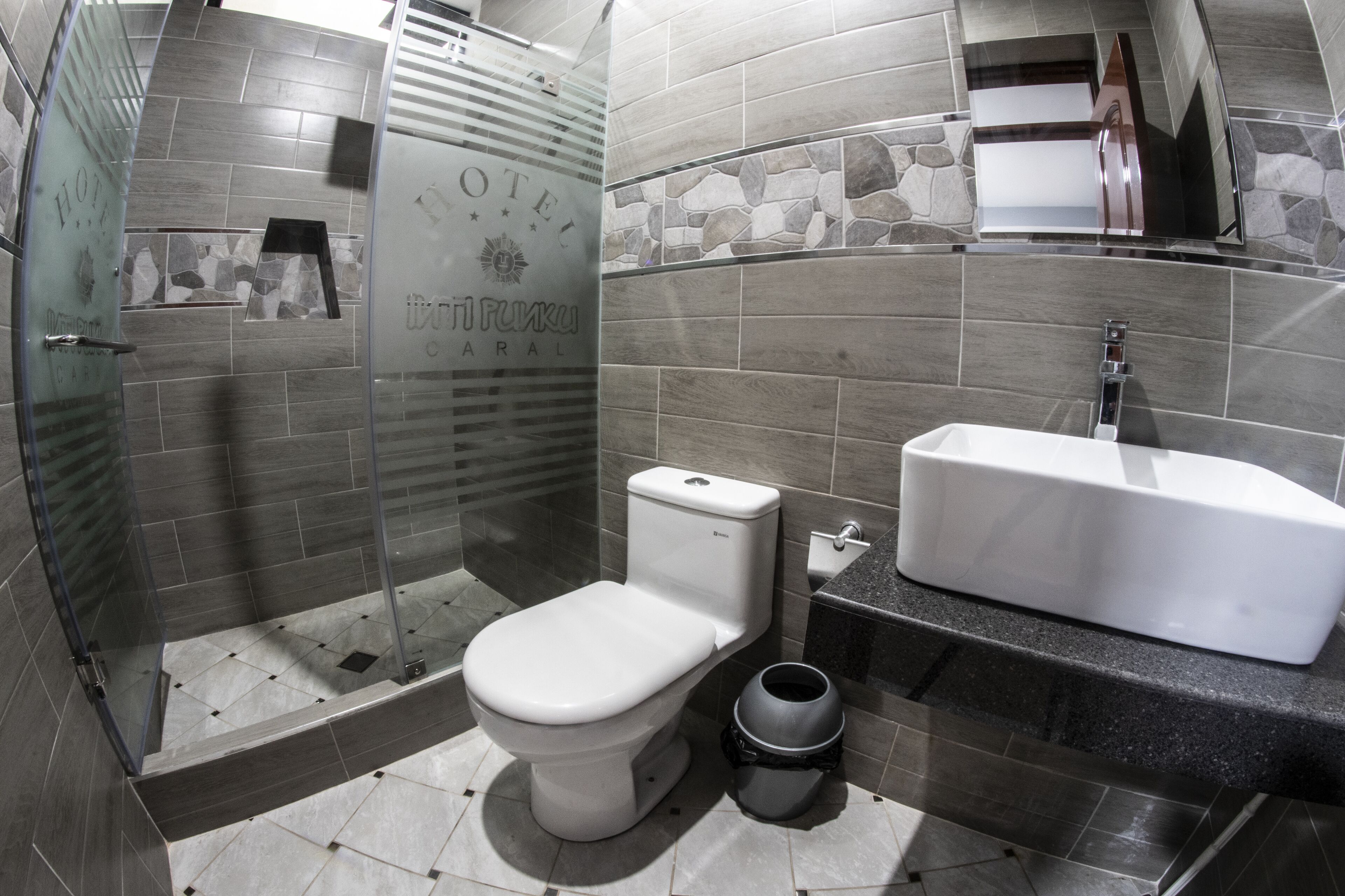 Un bagno moderno con doccia vetrata, un water e un lavandino.