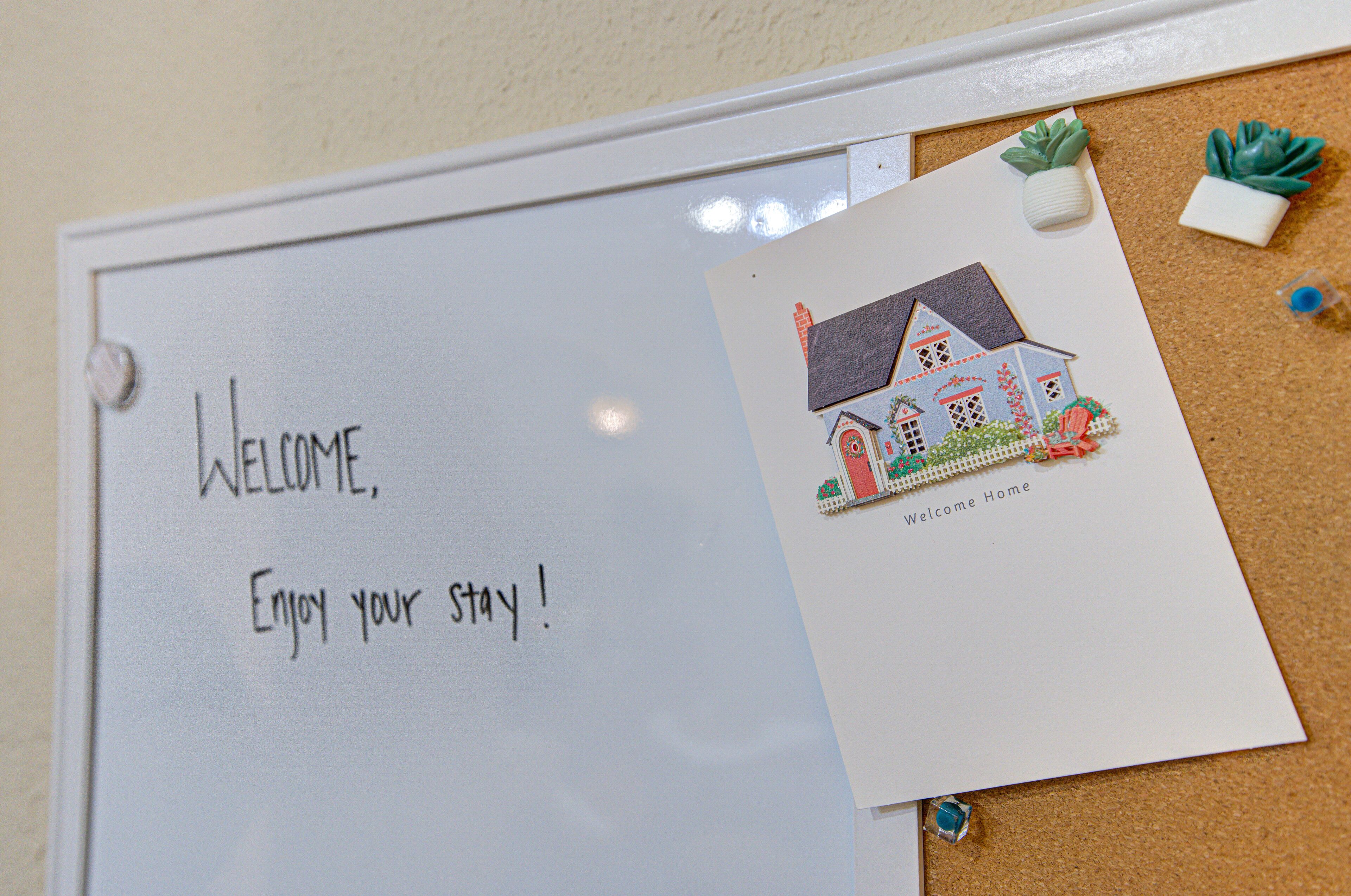 A whiteboard with "WELCOME, Enjoy your stay!" written on it, and a small house drawing with "Welcome Home" below it.