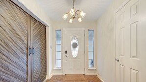 Un pasillo con una puerta de madera, una puerta blanca con ventanal y una puerta con un panel de vidrio decorativo.