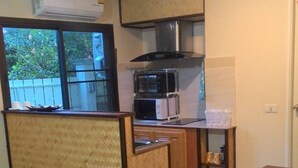 Eine kompakte Küche mit Mikrowelle, Backofen und einer kleinen Essecke mit Holztisch und Stühlen.