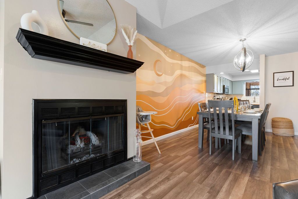A modern living room with a fireplace, dining area, and kitchen in the background.