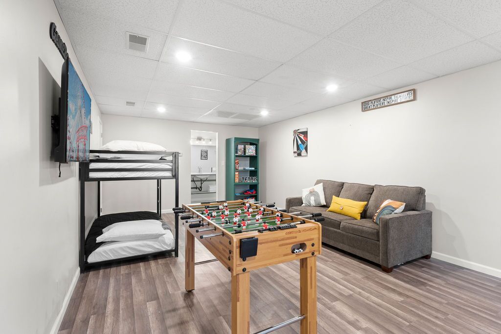 Um quarto com mesa de pebolim, beliches, sofá e televisão.