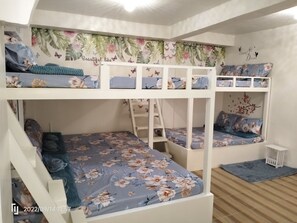 Cozy multi-level bunk bed room with a floral theme, featuring a white bunk bed and a tropical mural.