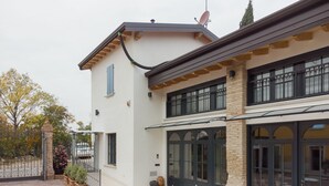A two-story building with a patio area featuring a round table and chairs. - Corte Mira (Lonato del Garda)