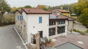 A two-story house with a tiled roof, a paved driveway, and a small outdoor seating area with tables and chairs. - Corte Mira (Lonato del Garda)