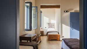 A bedroom with a wooden floor, a bed with a headboard, a bedside table, a wardrobe, and a window. - Corte Mira (Lonato del Garda)