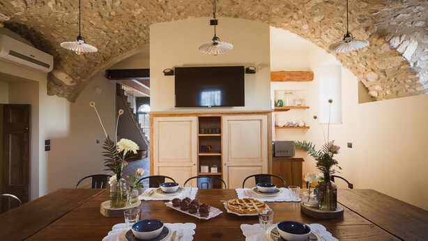 A dining area with a wooden table set for four, surrounded by stone walls and a stone ceiling. - Corte Mira (Lonato del Garda)