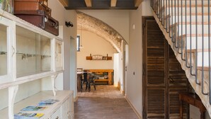 A hallway with a staircase, a wooden table with chairs, and a cabinet with glass doors. - Corte Mira (Lonato del Garda)