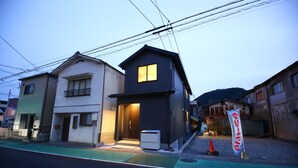 A residential building with a dark facade, a balcony, and a visible entrance. - PrimeRoomBeppu TATAMIsuite (Beppu)