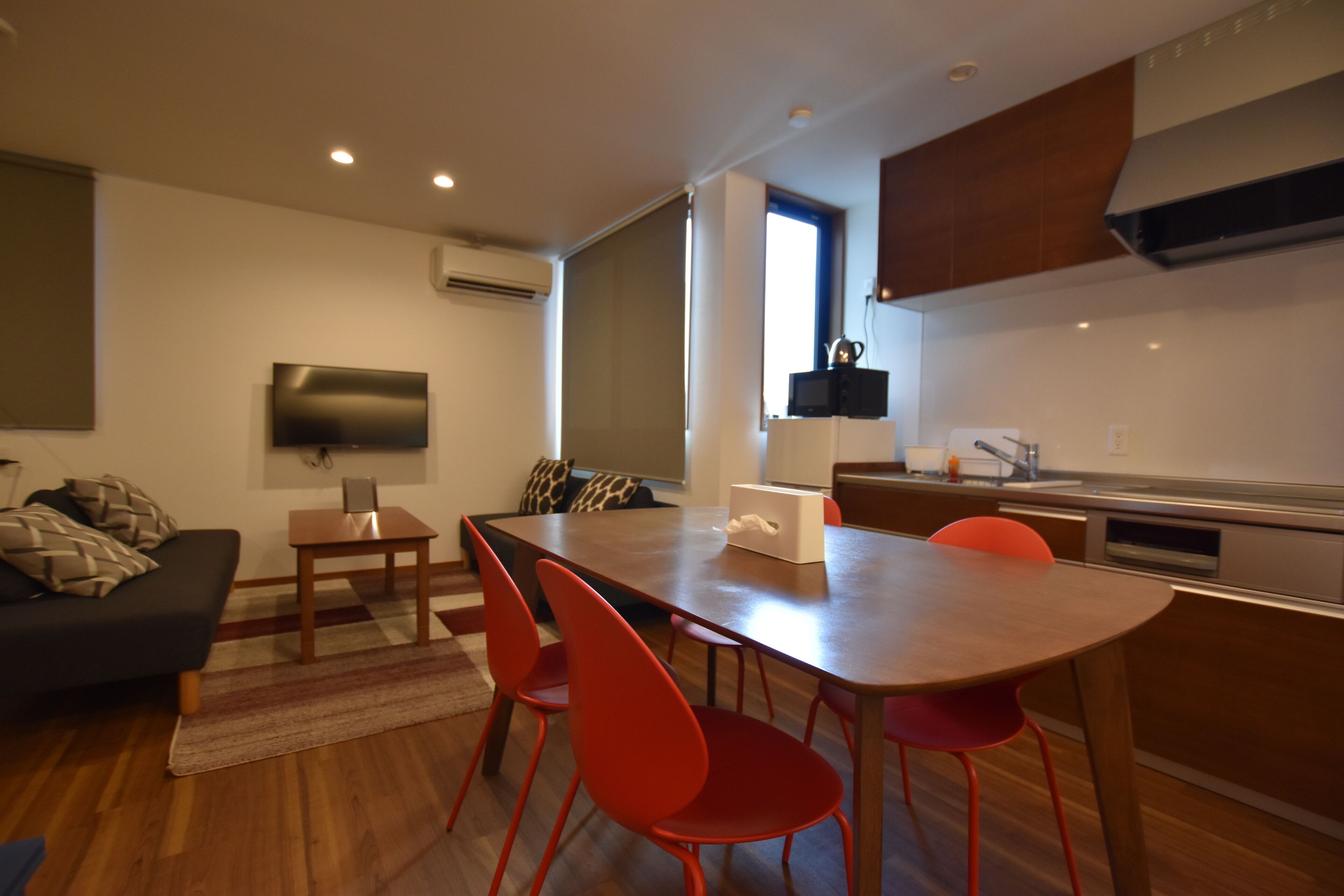 Una cocina moderna con comedor, piso de madera y televisor de pantalla plana.