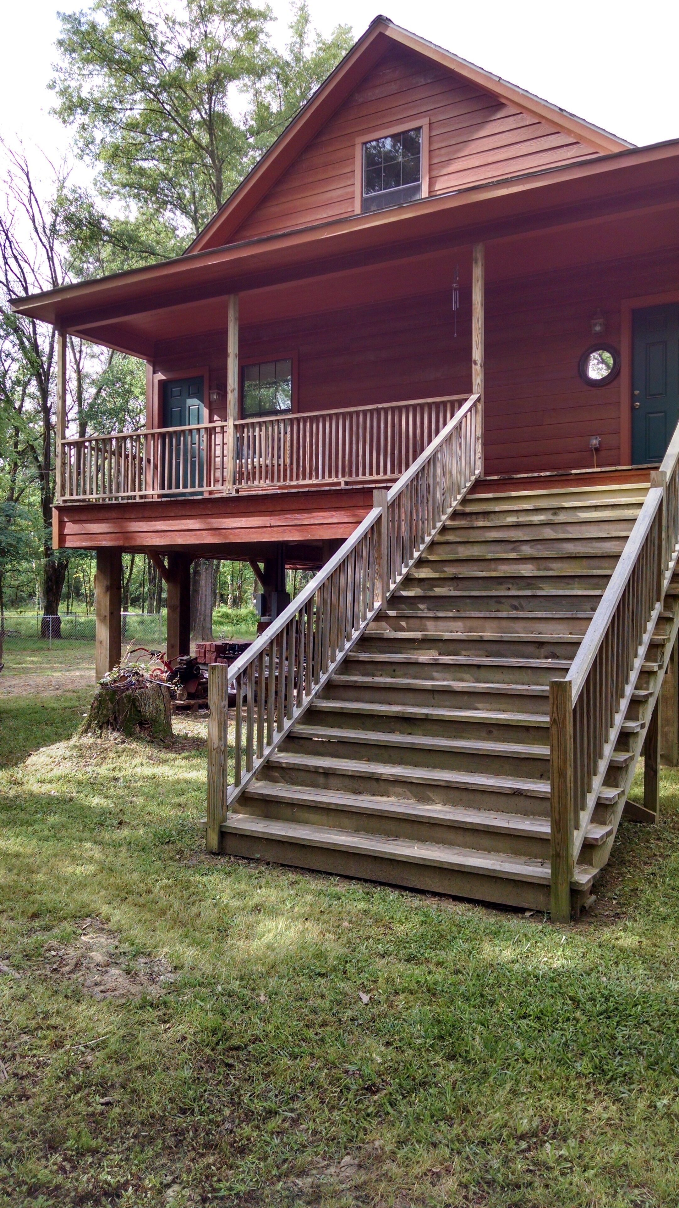 A wooden cabin with a covered porch and a staircase leading to the main entrance.