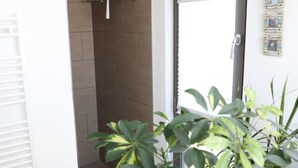 Un bagno moderno con doccia, porta asciugamani e una pianta in vaso.