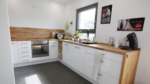 Una cucina moderna con mobili bianchi, un piano di lavoro in legno, un forno integrato e una finestra con vista.