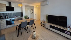 Een moderne keuken met een eethoek, een flatscreen televisie en een groot raam.