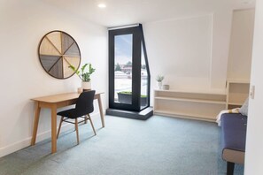 Habitació moderna amb escriptori, cadira i finestra gran.