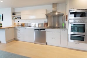 Una cocina moderna con electrodomésticos de acero inoxidable, armarios blancos y lavavajillas integrado.