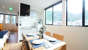 Habitación de hotel moderna con zona de comedor, kitchenette y un gran ventanal con vistas a las montañas.