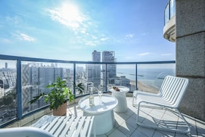 A balcony with a city view, a table with a bottle and glass, and two white chairs. - Awesome 2BR apt Balcony & pool access (Tel Aviv)