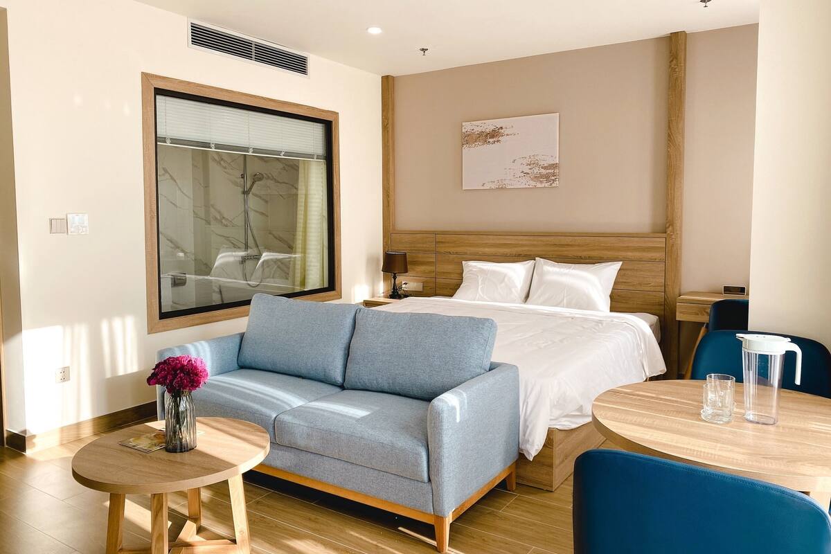 Ett hotellrum med en säng, en soffa, ett litet bord och en stol.