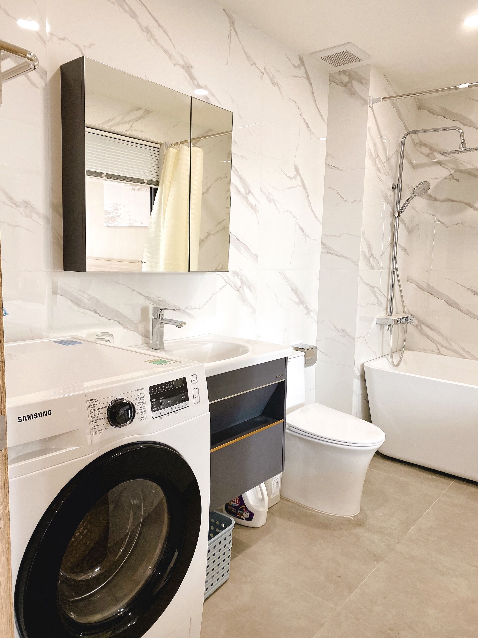 A modern bathroom with a washing machine, a sink, a toilet, and a bathtub.