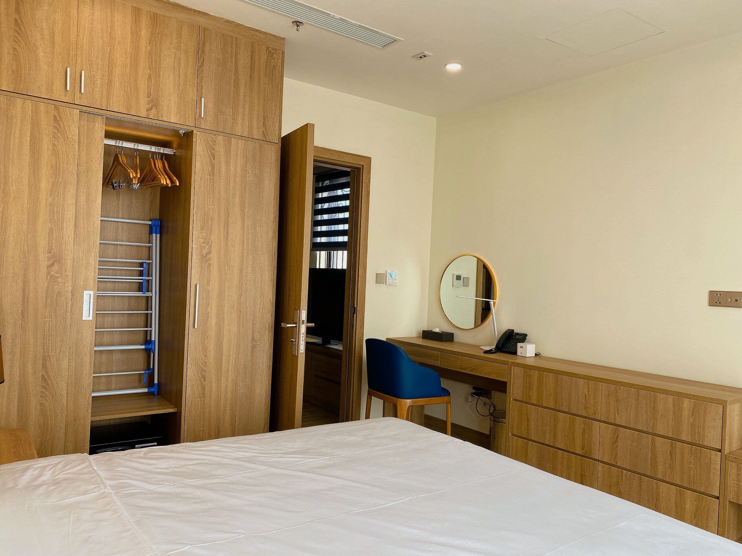 A bedroom with a bed, a desk with a chair, a wardrobe, and a mirror.