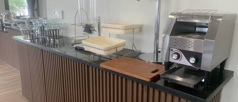 Un área de cocina moderna con cafetera, hervidor y lámpara.