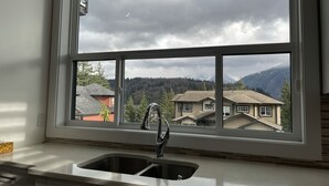A kitchen with a large window overlooking a residential area and mountains. - Gorgeous house on the top of the mountain in Chilliwack (Chilliwack)