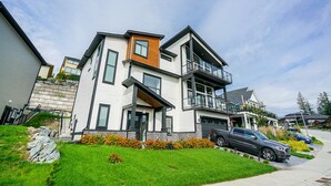A modern multi-story residential building with a balcony, a garage, and a driveway with parked cars. - Gorgeous house on the top of the mountain in Chilliwack (Chilliwack)