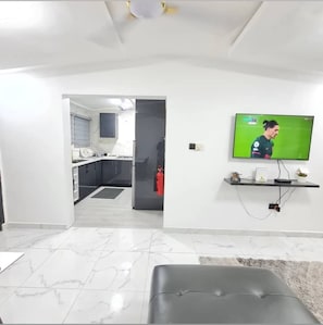 Relax in this stylish living room with a flat-screen TV, comfortable leather ottoman, and a kitchen just steps away.