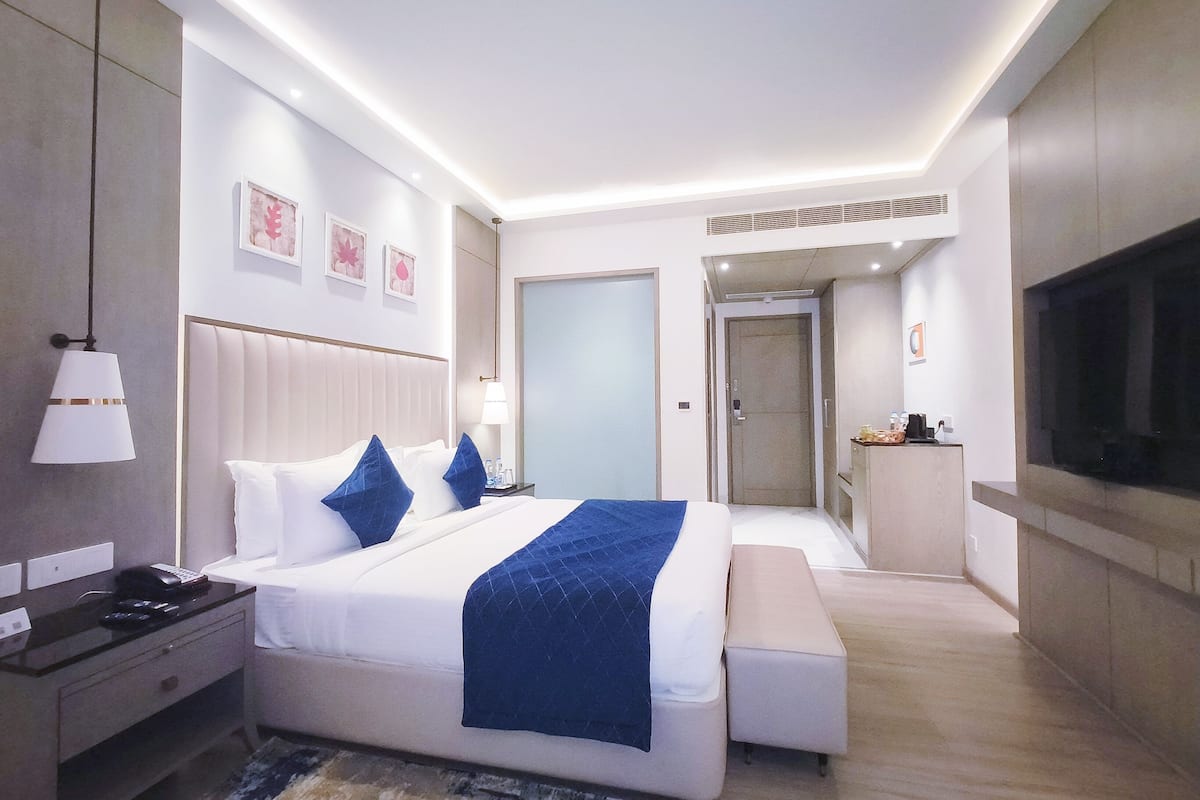 A modern hotel room with a large bed, bedside tables, a desk, and a television.