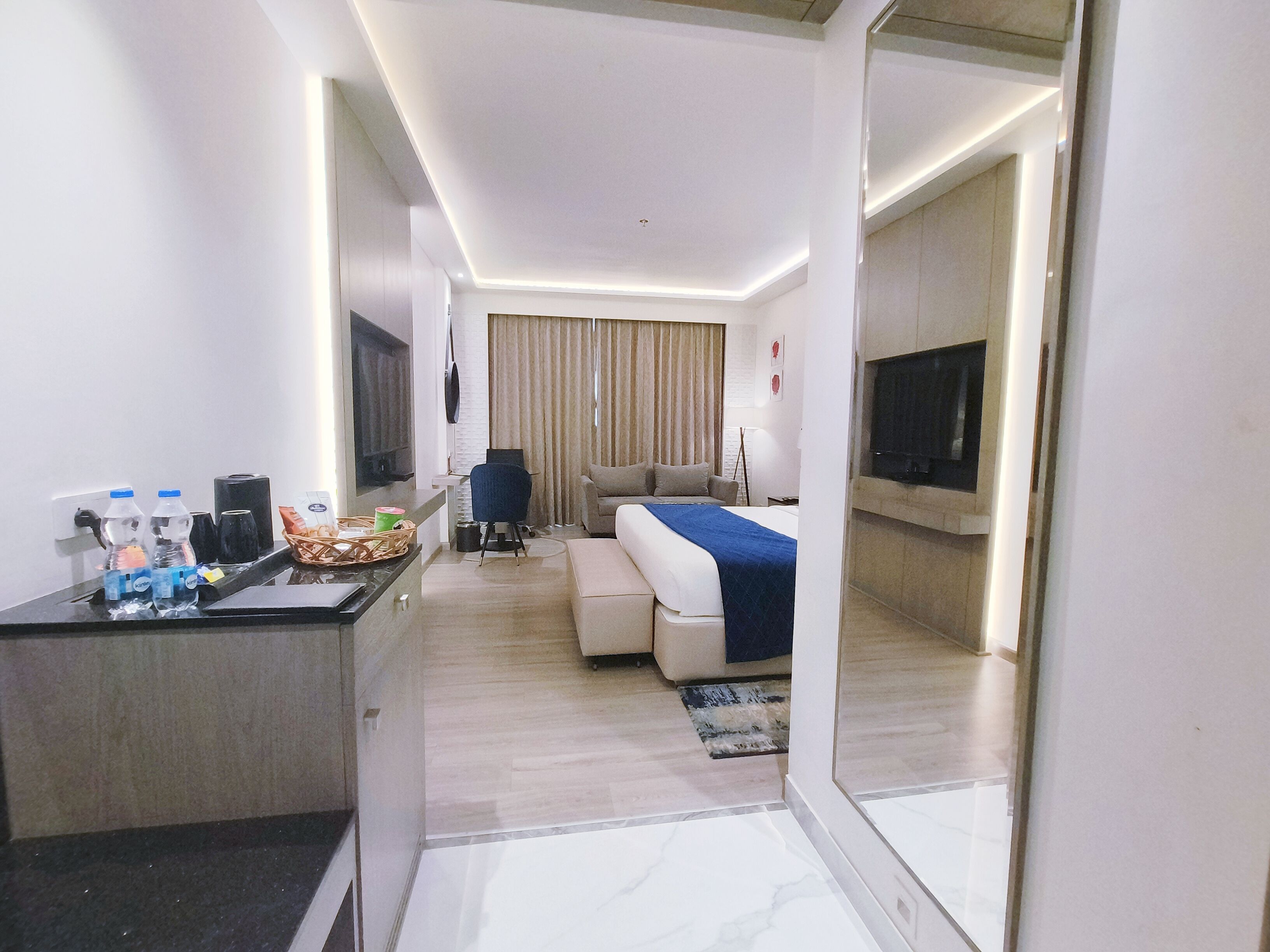 Una habitación de hotel moderna con una cama, un escritorio con computadora, una silla y un televisor.