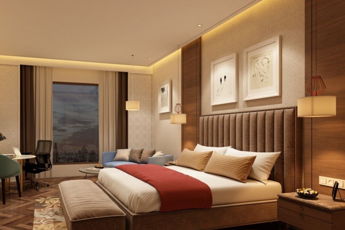 Una habitación de hotel moderna con una cama grande, un escritorio, una silla, un televisor y obras de arte en las paredes.