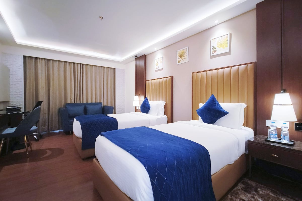 A hotel room with two beds, a desk, and a chair.