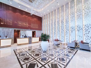 Un moderno vestíbulo de hotel con mostrador de recepción, zona de estar y paneles decorativos en la pared.