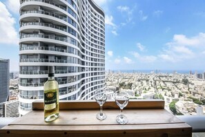 A bottle of Daniel Selected white wine and two glasses on a wooden surface with a cityscape view. - MAMAD - Luxe Apt in Top Tel Aviv Neighborhood (Tel Aviv)