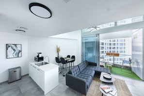 A modern apartment with a kitchen, dining area, and living room with a large window overlooking a cityscape.