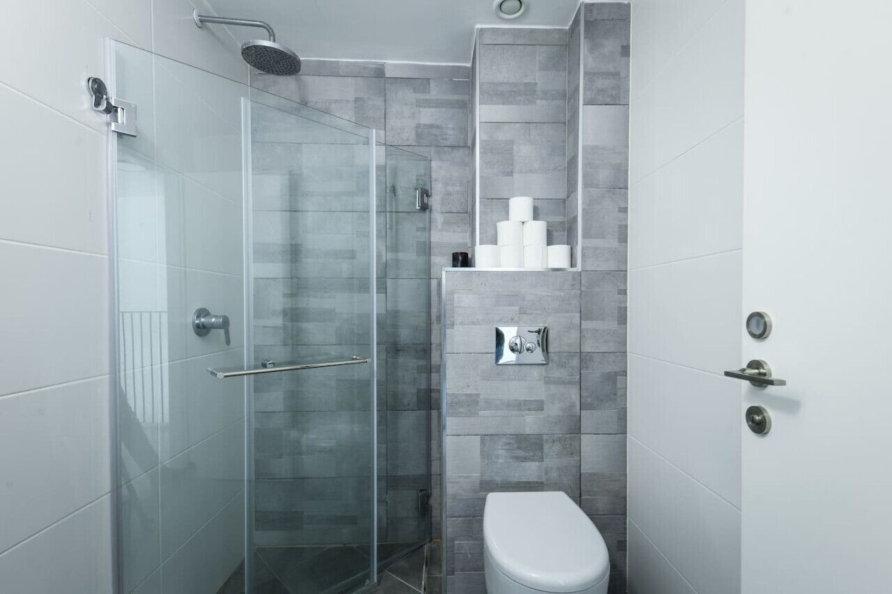 Een moderne badkamer met een douchecabine van glas, een toilet en een plank met toiletartikelen.