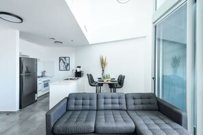 A modern kitchen with a dining area, a sofa, and a large window. - MAMAD - Luxe Apt in Top Tel Aviv Neighborhood (Tel Aviv)