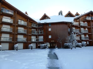 A multi-story wooden building with balconies and a snow-covered entrance.