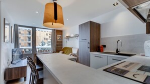 A modern kitchen with a large island, wooden cabinets, and a pendant light.