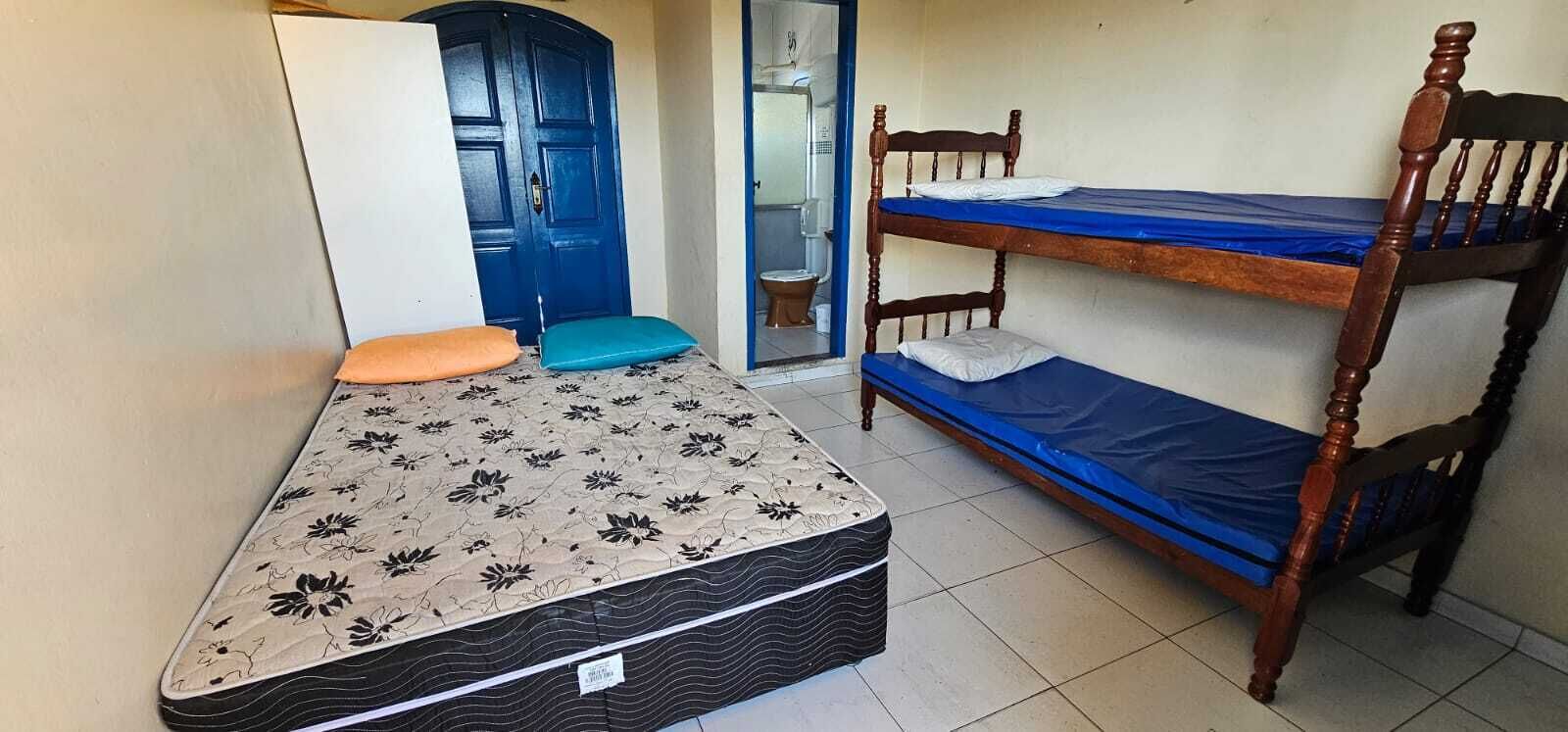 Ein Zimmer mit Etagenbett, einem Einzelbett mit Blumenmuster und einer blauen Tür.
