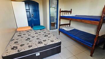 Ein Zimmer mit Etagenbett, einem Einzelbett mit Blumenmuster und einer blauen Tür.