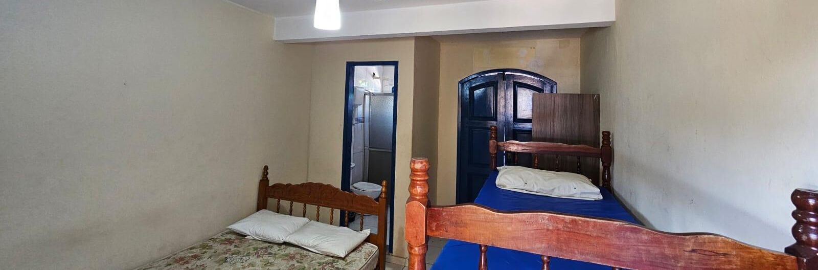 Una habitación pequeña con dos camas de madera, una puerta y un espejo.