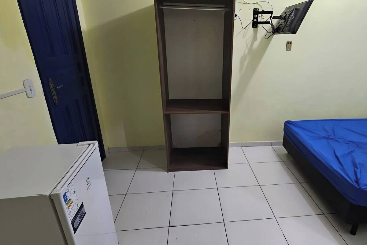 Une petite pièce comprenant un lit, une armoire et un bureau avec un ordinateur.