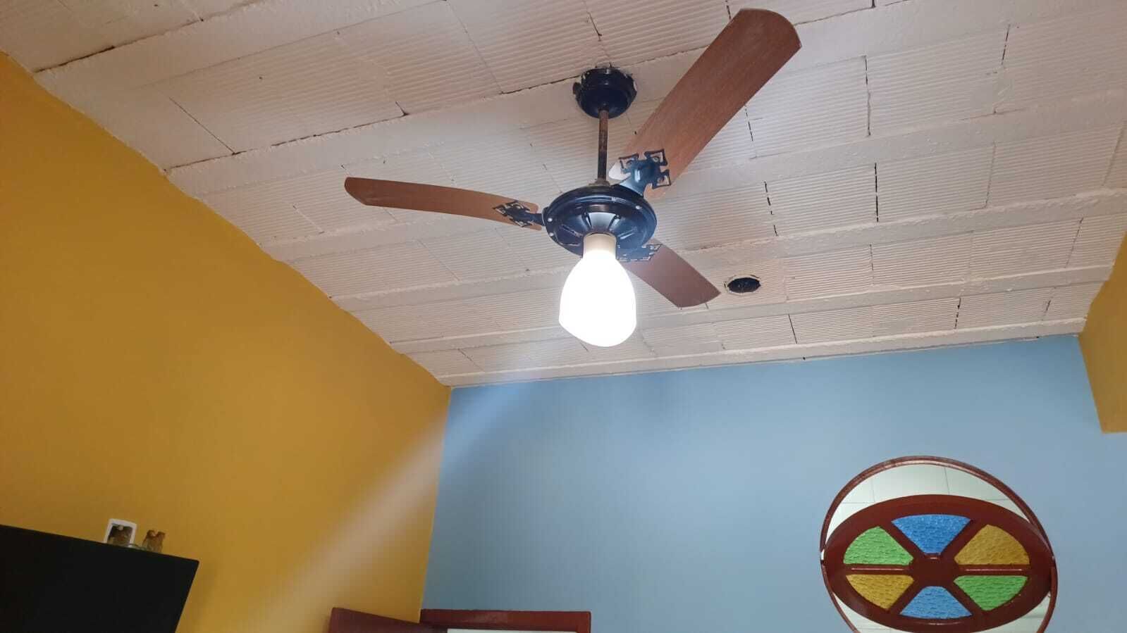 A ceiling fan with a light fixture in a room with yellow and blue walls.