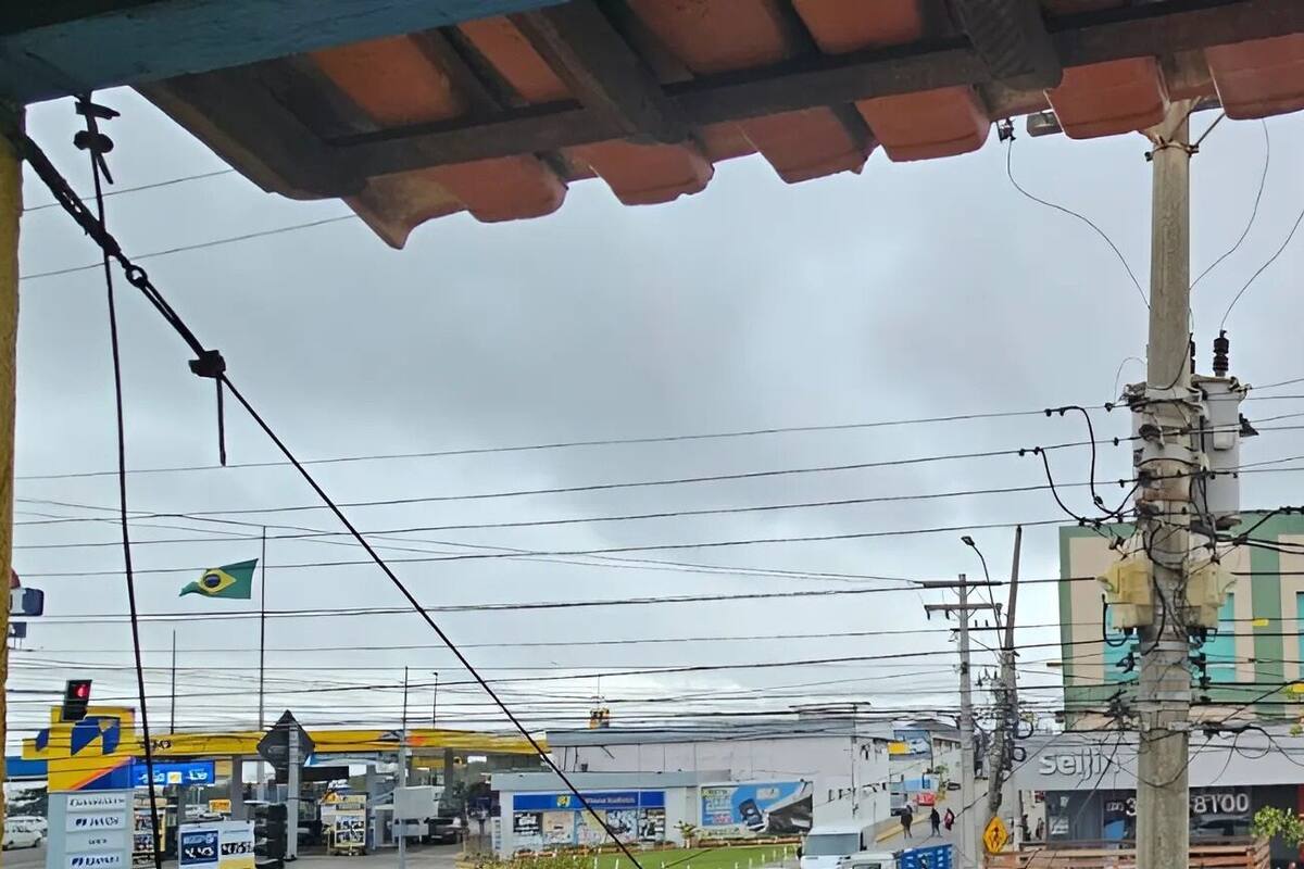 Une vue de rue avec une concessionnaire Nissan, une station-service et un immeuble à la façade verte et beige.