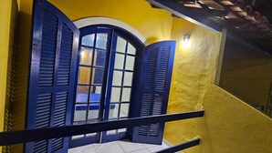 Een balkon met blauwe luiken en een gele muur.