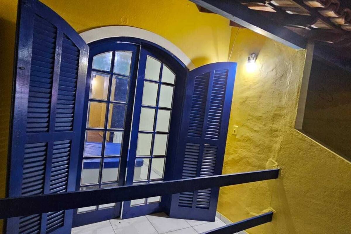 Un balcon avec des volets bleus et un mur jaune.